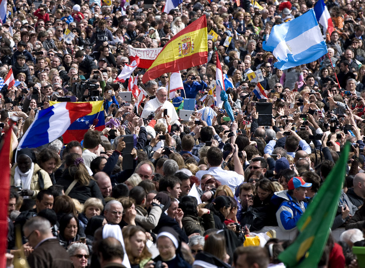 I fedeli in piazza San Pietro assistono con le loro bandiere alla messa di Pasqua, il 31 marzo (Alessia Giuliani)